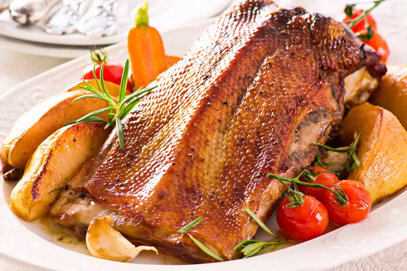 Goldbraun gebratene Gänsebrust mit Äpfeln und Tomaten