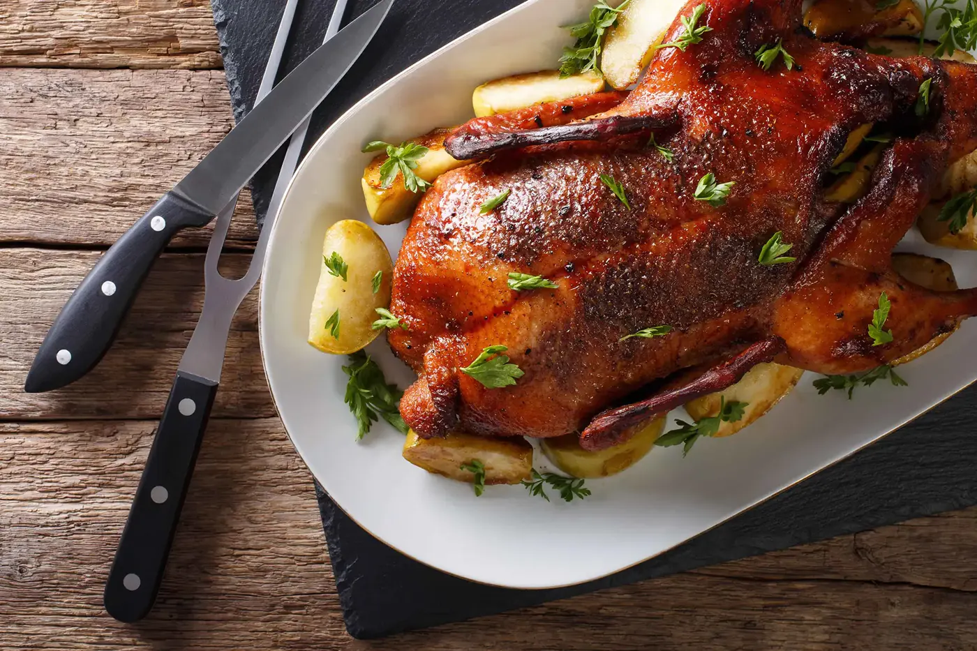 Knusprig gebratene ganze Gans mit Kräutern auf einer Servierplatte
